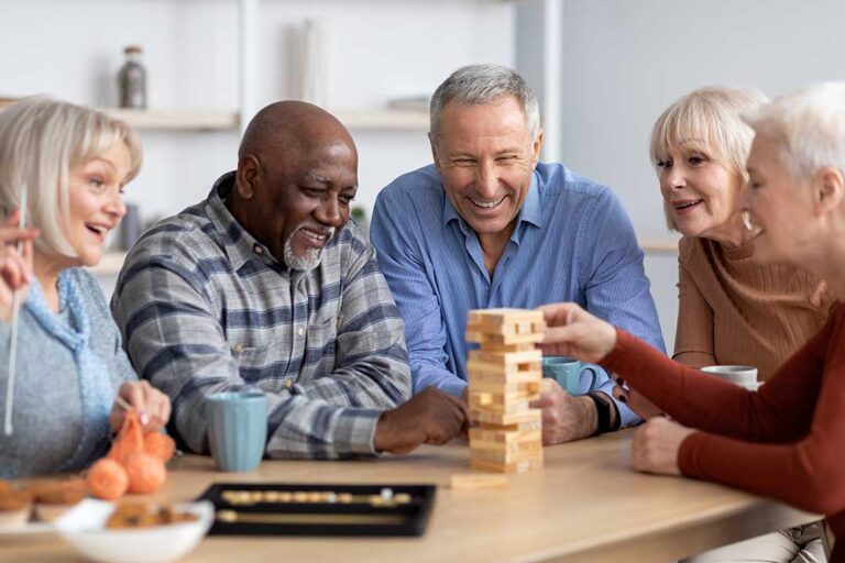Elderly residents gather together at a table doing arts and crafts with seasonal decorations.